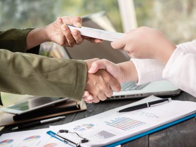 Business people shaking hands, finishing up meeting. businessman giving money to his partner while making contract - bribery and corruption concepts.